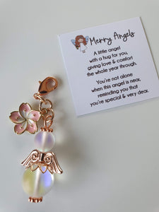 This is a picture of a clear angel hug with rose gold wings and feet and a rose gold and pink flower charm attached