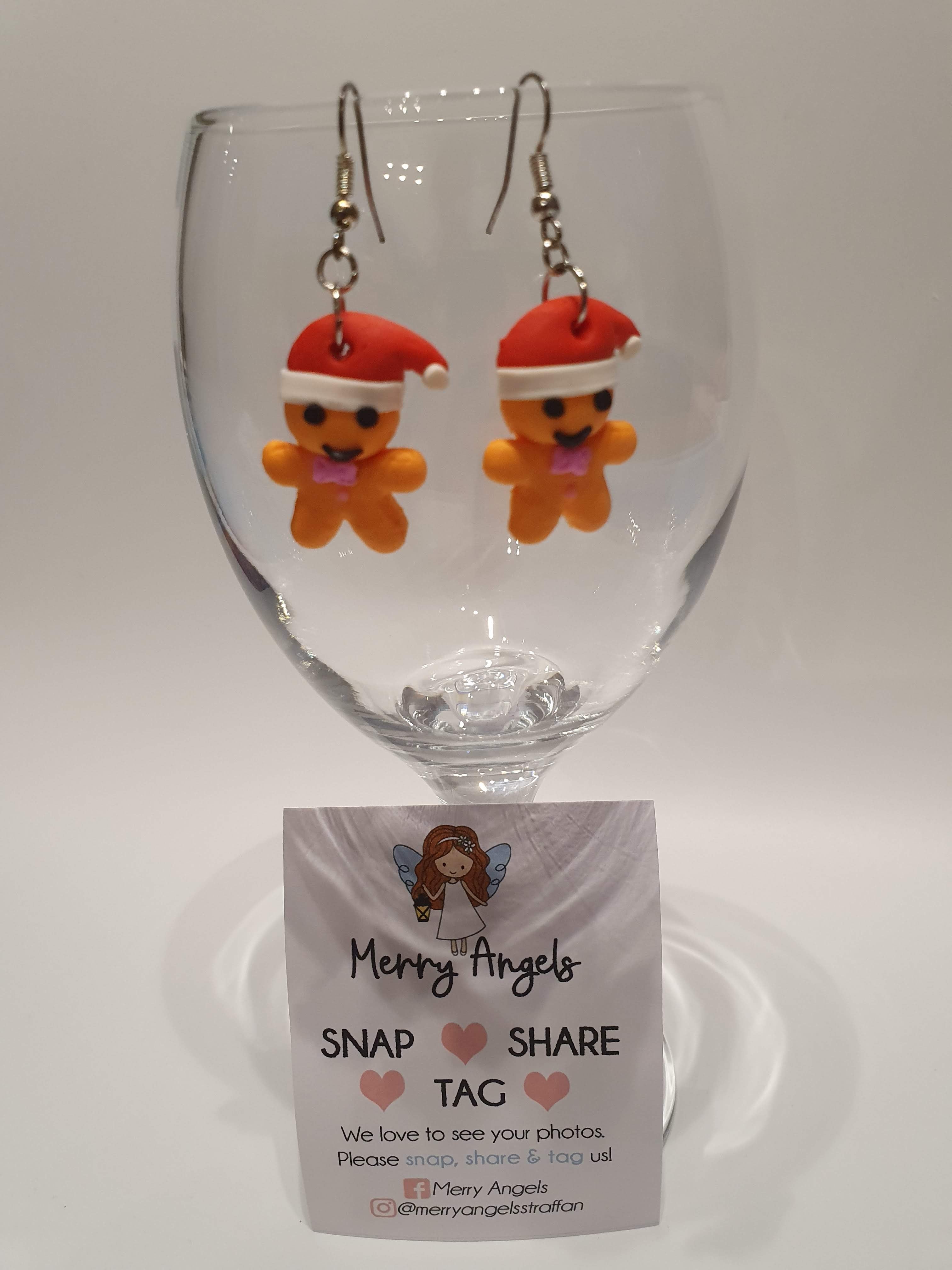 This is a picture of a pair of gingerbread man earrings hanging over a wine glass