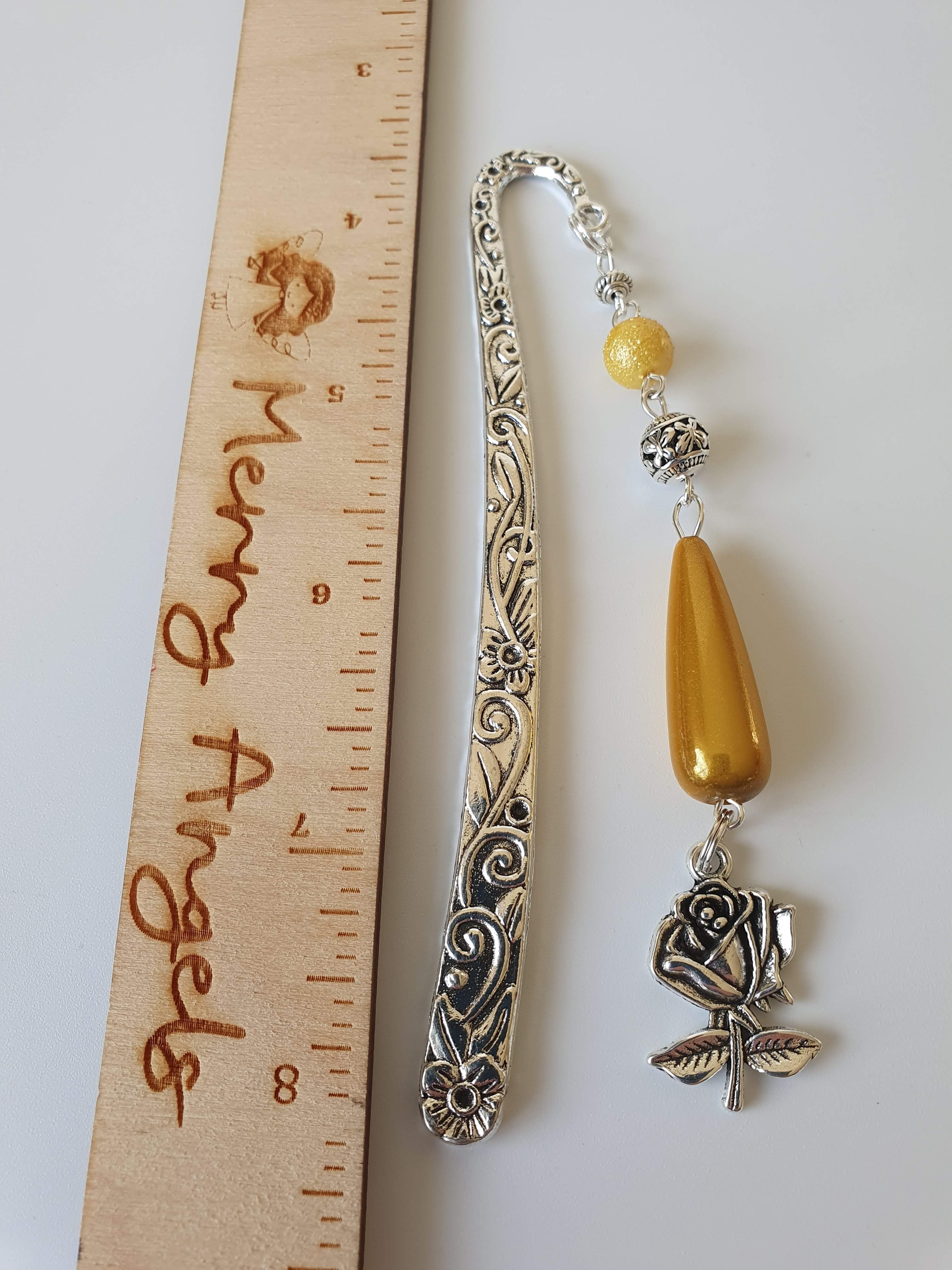 This is a picture of a silver bookmark with yellow beads and a silver rose charm