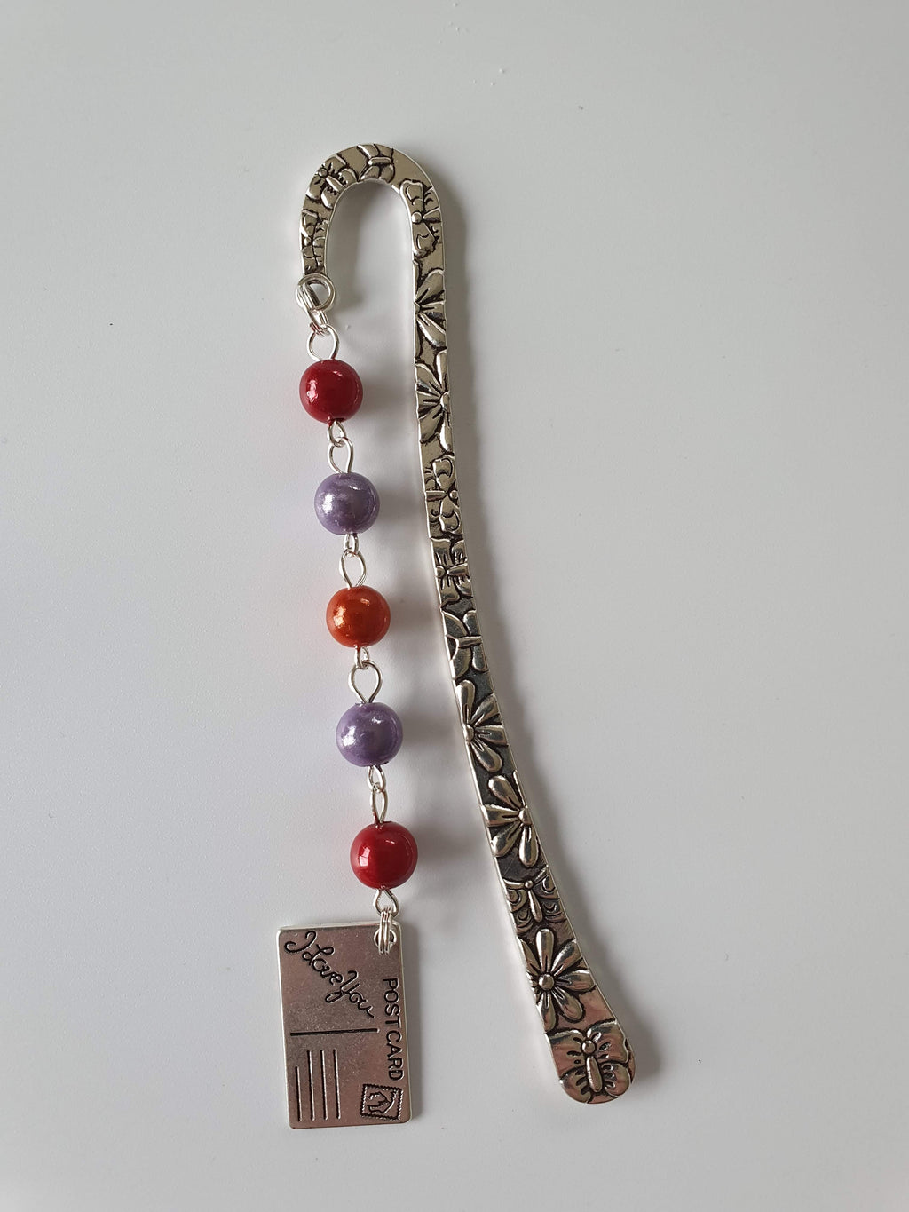 This is a picture of a silver bookmark with red and purple beads and an 'I love you' postcard charm attached