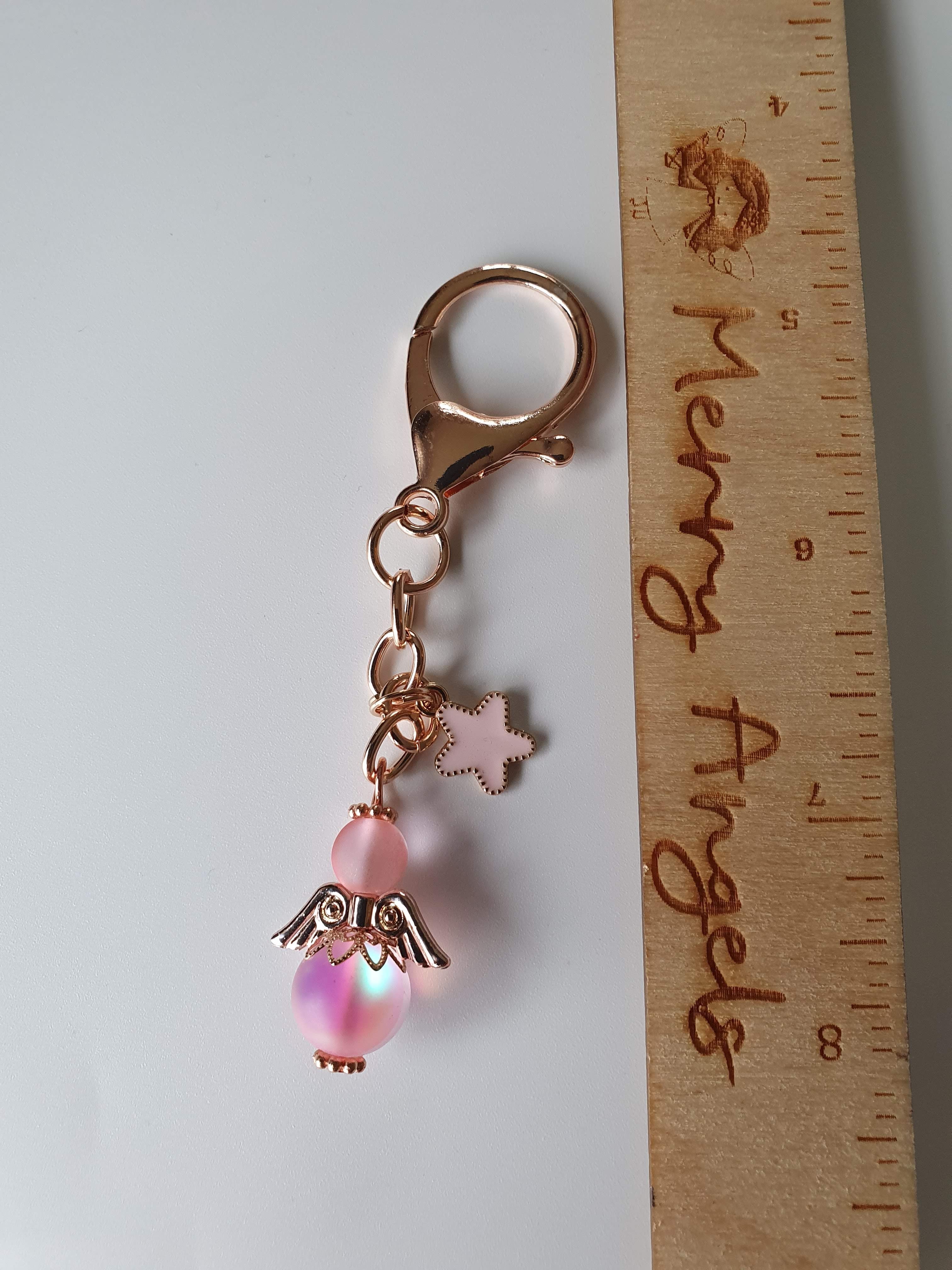 This is a picture of a rose gold angel keyring with a rose gold and pink star charm. The angel is also pink. 