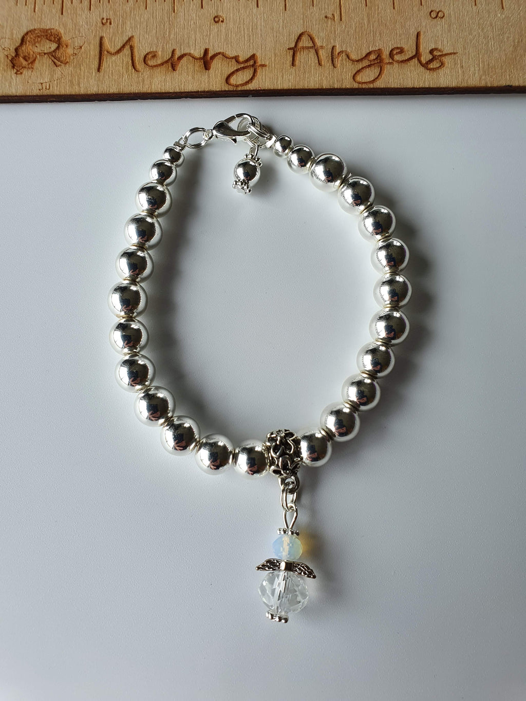 This is a picture of a silver bead bracelet with a clear angel hanging from the centre of the bracelet
