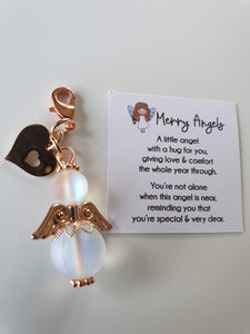 This is a picture of a clear angel hug with rose gold wings and feet and a rose golld heart charm attached 