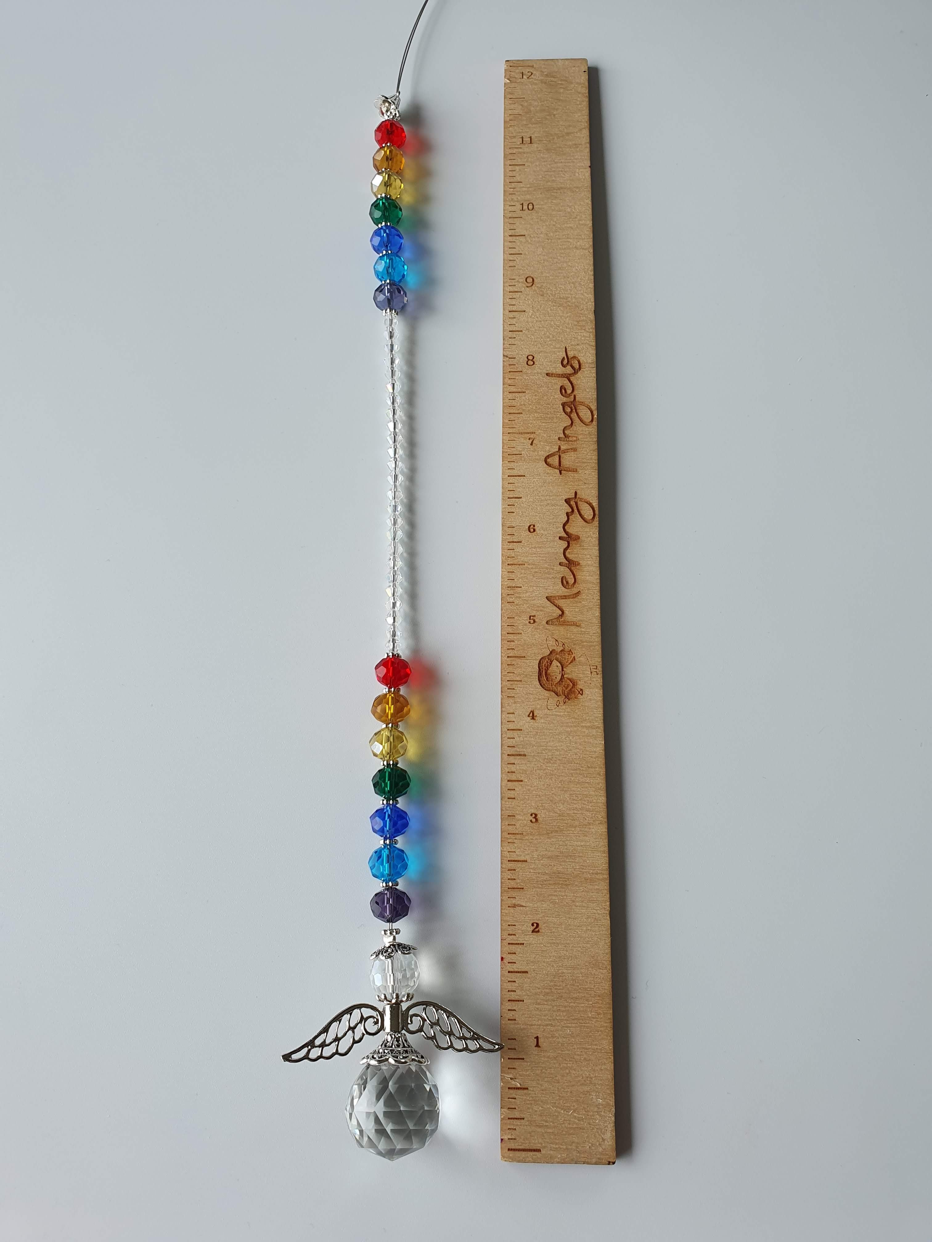 This is a picture of an angel rainbow 10.5 inch suncatcher laid out beside a ruler