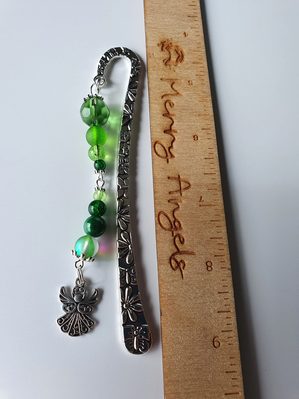 This is a picture of a silver bookmark with green beads and a silver angel