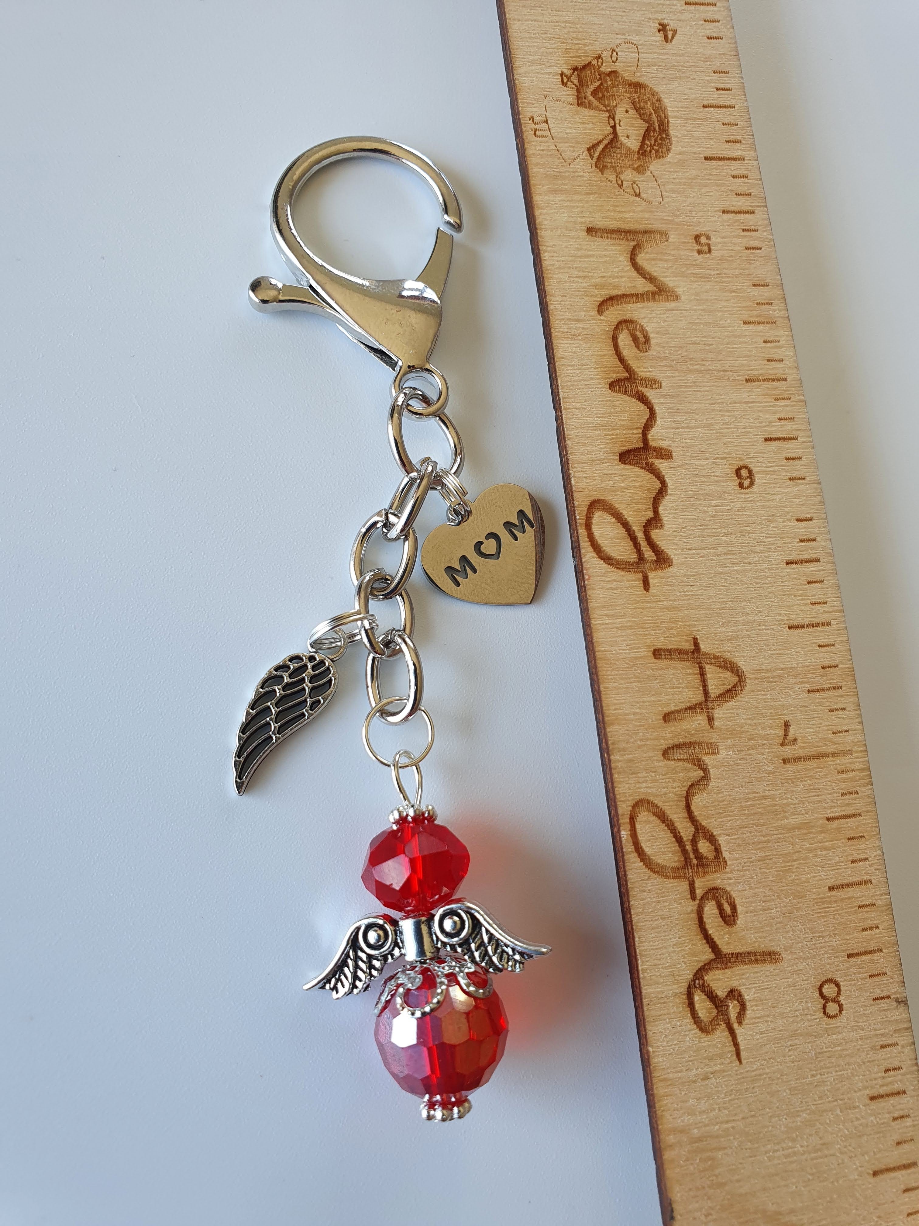 This is a picture of a silver angel keyring with two silver charms. The angel is red