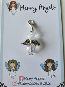 This is a picture of a clear angel hug with silver wings and feet. It is attached to a card with the words Merry Angels written on it. 