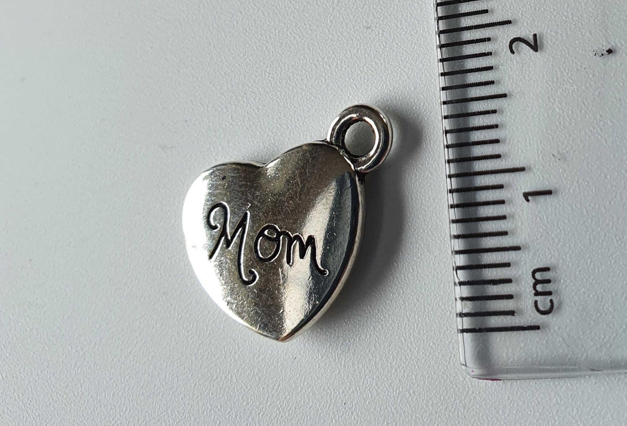 Silver charm with 'Mom' engraved on it