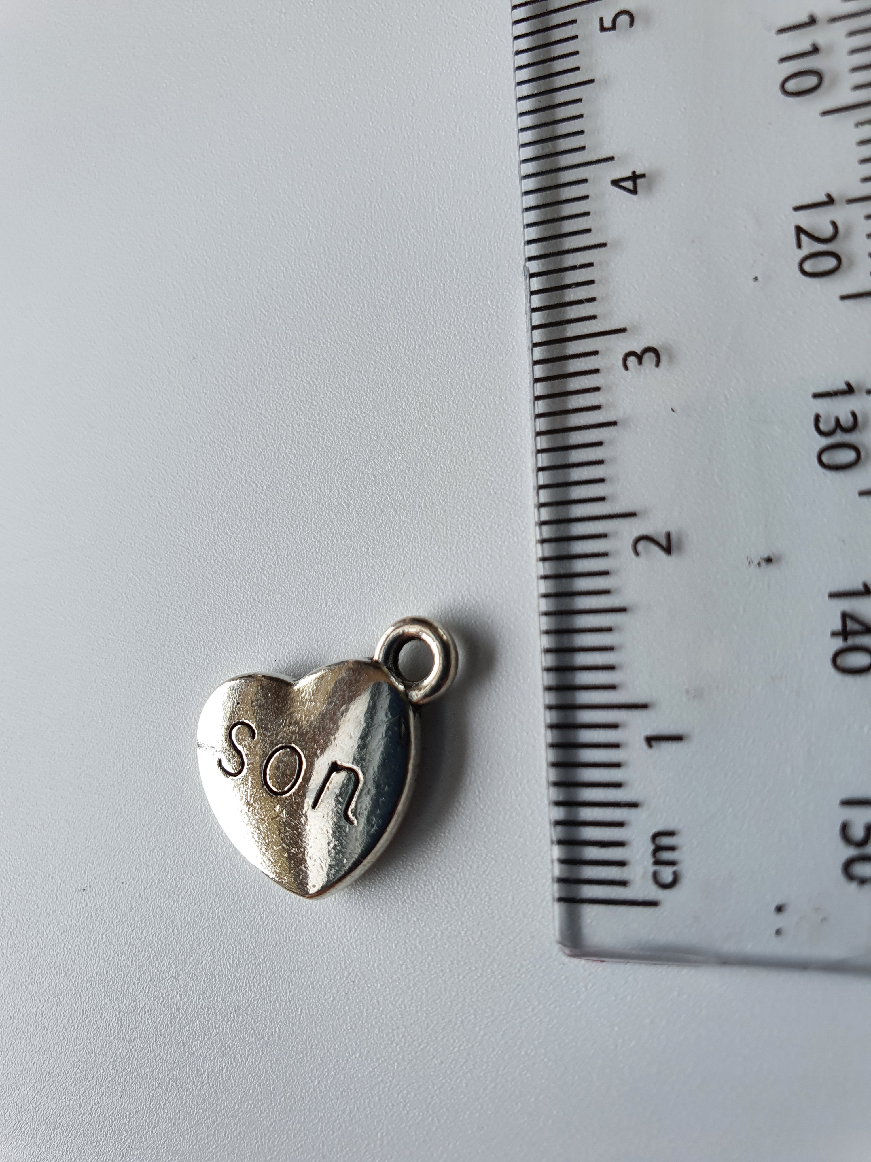 Silver charm with 'son' engraved on it