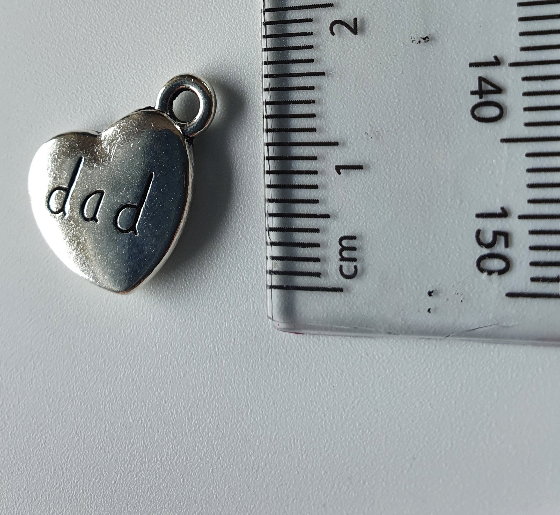 Silver charm with 'dad' engraved on it