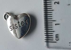 Silver charm with 'sister' engraved on it