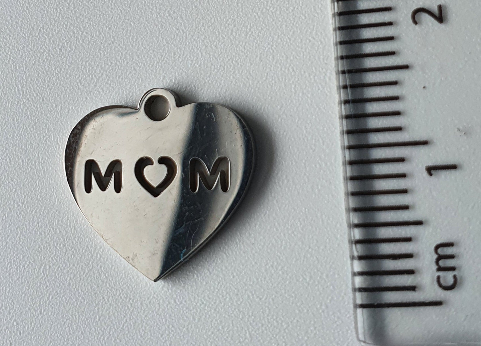 Silver charm with 'MOM' engraved on it