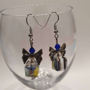 This is a picture of a pair of Christmas present earrings hanging over a wine glass