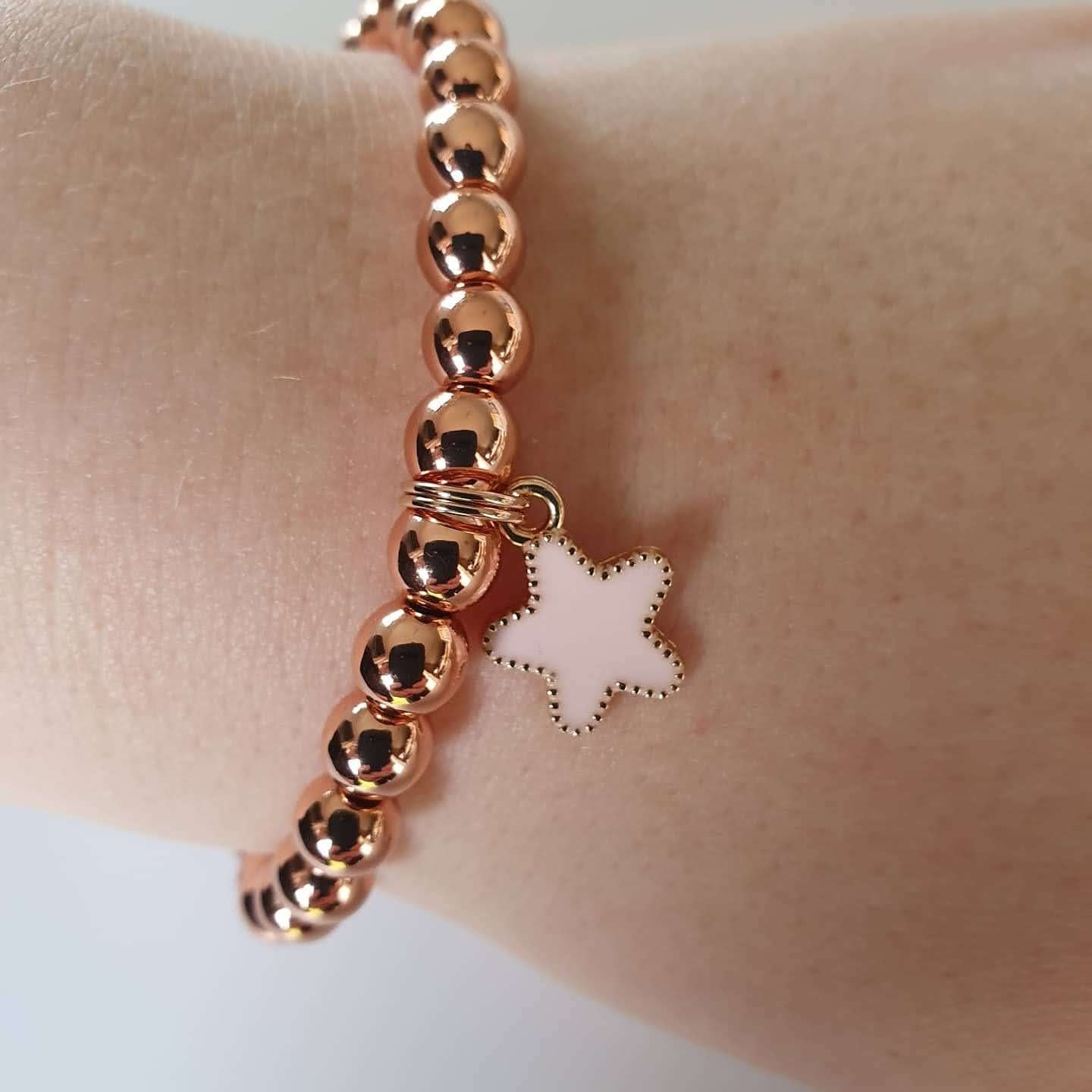 This is a picture of a rose gold bracelet with a star charm on a wrist