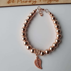 This is a picture of a rose god bracelet with a feather charm 