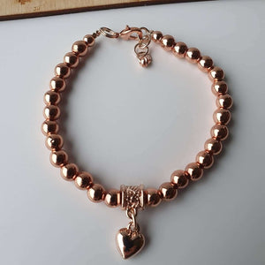This is a picture of a rose gold bracelet with a heart charm