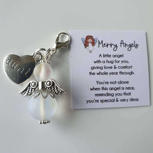 This is a picture of a clear angel hug with silver wings and feet and a silver heart charm with the word 'aunt' engraved on it. There is also a poem about angels printed on a piece of card. 