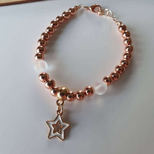 This is a picture of a rose gold and clear bracelet with a rose gold and white star charm hanging from it