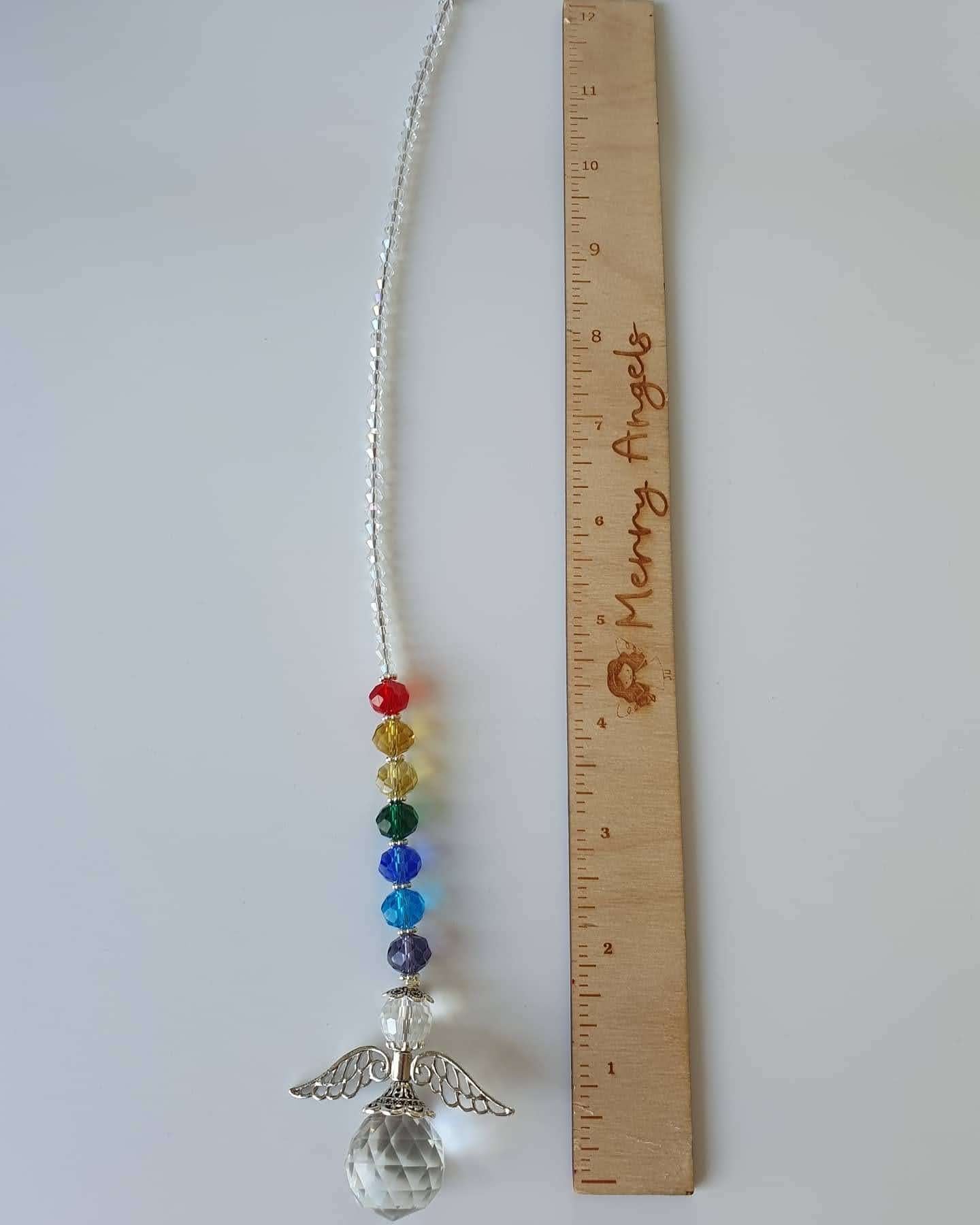 This is a picture of an angel rainbow 10.5 inch suncatcher laid out beside a ruler