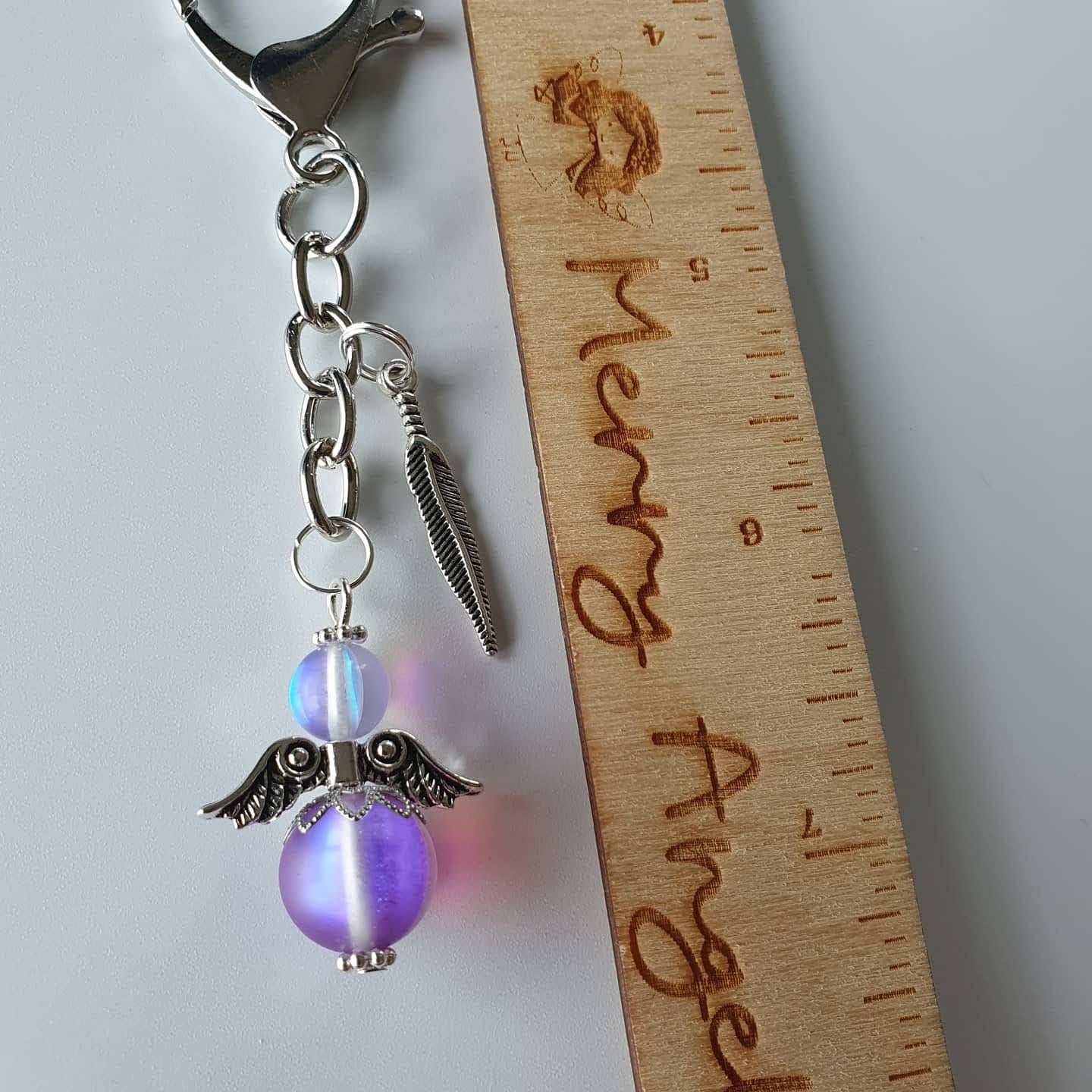 This is a picture of a silver angel keyring with a silver feather charm attached. The angel is a beautiful lilac colour