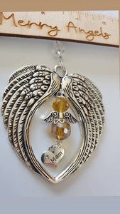This is a picture of a silver angel wing hanging charm with a yellow angel in the centre and a 'mam' charm hanging from the bottom of the angel
